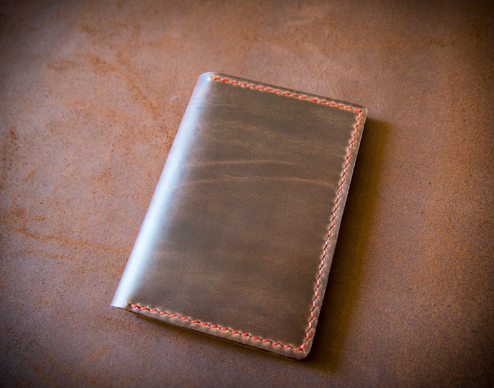 Polished brown leather passport wallet stitched with red thread closed