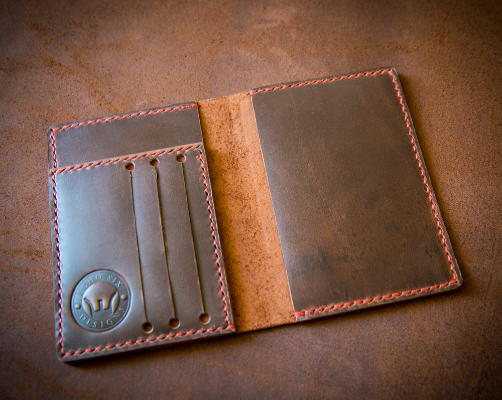 Polished brown leather passport wallet stitched with red thread and opened up