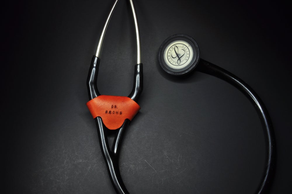 Tan leather stethoscope identification tag wrapped around a black cardiology stethoscope 