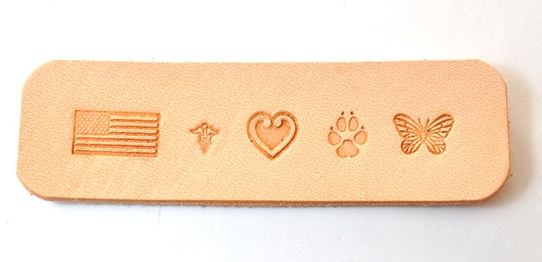 Symbols for stethoscope identification tag including an American flag, caduceus, heart, dog paw print, and a butterfly all pressed into a piece of leather